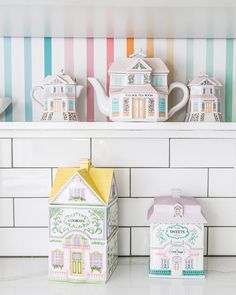 some little houses are sitting on the shelf in front of a tile backsplash