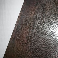 a close up view of a brown leather textured table top with white walls in the background