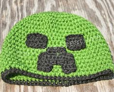 a crocheted beanie with a video game controller on it's face