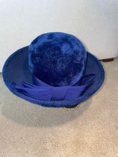 Elevate your style with this Imported Royal Blue Designer Hat by Mr. John Jr., a true vintage gem straight from the 1960s. Crafted in Austria, this hat is a testament to both quality and timeless fashion. Renowned for their elegant and unique creations, Mr. John Jr. is a name synonymous with exceptional style. This hat exudes an air of sophistication with its imported royal blue fabric, making it a statement piece in any fashion ensemble. The delicate grosgrain ribbon bow adds a touch of charm a Blue Formal Winter Hat, Formal Blue Winter Hat, Vintage Blue Hat With Flat Brim, Vintage Blue Short Brim Hat, Vintage Blue Flat Brim Hat, Blue Fitted Wide Brim Cloche Hat, Blue Wide Brim Cloche Hat, Classic Blue Hats With Curved Brim, Classic Blue Hat With Curved Brim