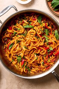 a pan filled with noodles and vegetables on top of a table next to other dishes