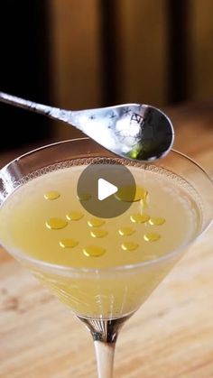 a spoon with some liquid in it on top of a glass filled with lemon juice