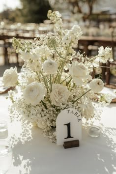 a table topped with white flowers and a number one centerpiece on top of it