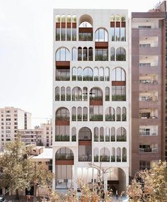 an apartment building with many windows and balconies on the top floor, surrounded by tall buildings