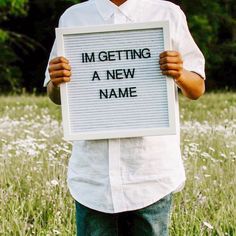 a man holding up a sign that says i'm getting a new name in front of him