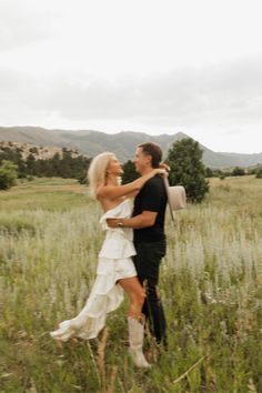 a man and woman are walking through the grass