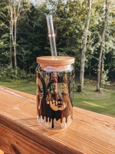 a glass jar with a straw sticking out of it sitting on a wooden table outside