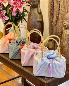 three bags with bows are sitting on a table next to some flowers and a statue