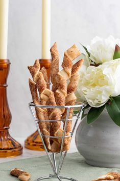 there are some crackers in a glass bowl on the table next to flowers and candles