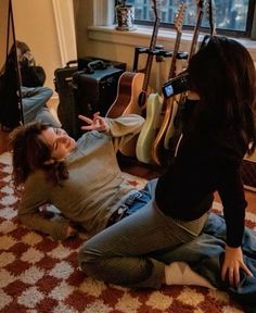 two women sitting on the floor in front of guitars