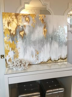 an abstract painting with gold and silver paint on a white shelf next to a window