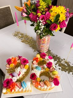 two cakes with flowers in the middle on a table next to a vase full of flowers