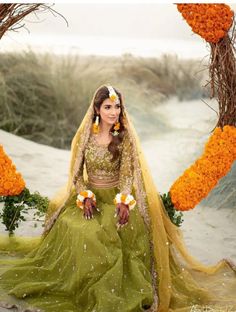 a woman in a green and yellow wedding dress with flowers on the ground next to her