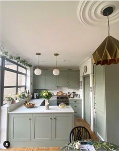 a kitchen with green cabinets and white counter tops next to a dining room table in front of a large window