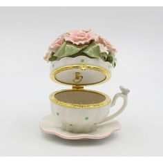 a white tea cup with pink roses and gold trimmings sitting on top of a saucer