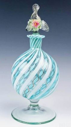 a blue and white striped glass vase with a flower in it's top sitting on a table