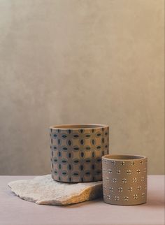 two cups sitting next to each other on top of a table with a cloth under them