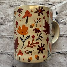 a coffee cup decorated with flowers and leaves on a stone wall background is seen in this image