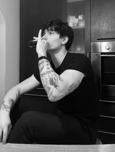 a man sitting on top of a kitchen counter drinking from a wine glass in his hand