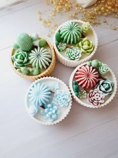 four small cupcakes decorated with flowers and succulents