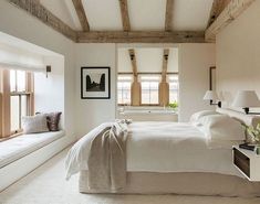 a bedroom with white bedding and wooden beams