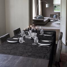 a dining room table with place settings and candles on the dinner table set for four