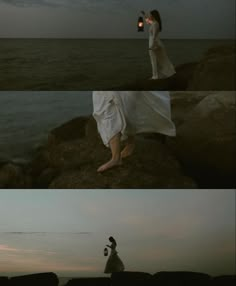 two people standing on rocks near the ocean at night and one person holding an umbrella