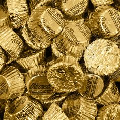 gold foiled chocolate candies are piled on top of each other in this black and white photo