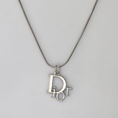 Authentic Christian Dior logo pendant set on a stainless steel 18 inch chain. Luxury Silver Jewelry With Silver-tone Logo, Affordable Classic Silver Charm Necklaces, Christian Dior Jewelry Vintage, Saint Laurent Necklace Silver, Vintage Silver Necklace With Logo Charm, Silver Charm Necklace With Logo As Gift, Luxury Silver Charm Necklace With Round Pendant, Christian Dior Logo, Bday List