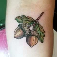 an acorn tattoo with leaves and nuts on the side of a woman's leg