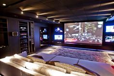 a living room with couches and large screen televisions on the wall behind them