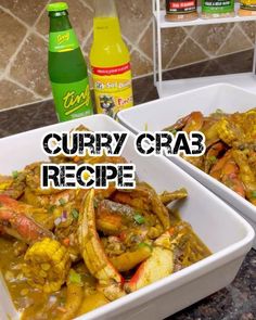 two white bowls filled with curry crab and vegetables next to bottles of soda on the counter