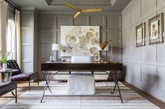 a living room filled with furniture and paintings on the wall next to a desk in front of a window