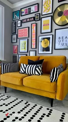 a living room filled with lots of pictures on the wall and a yellow couch covered in black and white pillows