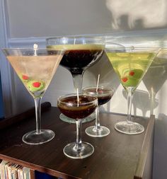 three martini glasses filled with different types of drinks