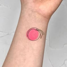 a small pink apple tattoo on the wrist