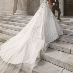 the bride and groom are walking down the steps together in their wedding gowns,