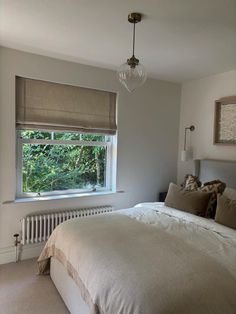 a bed sitting under a window next to a radiator in a room with white walls