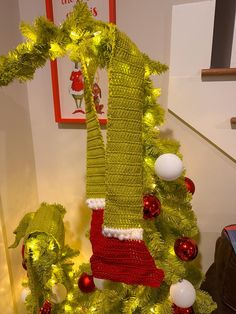 a christmas tree decorated with green and red stockings, ornaments and lights on the bottom