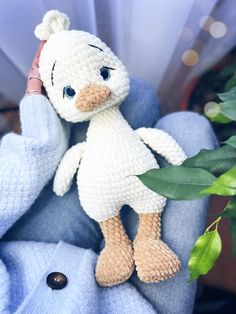 a crocheted stuffed animal sitting on top of a blue chair next to a potted plant