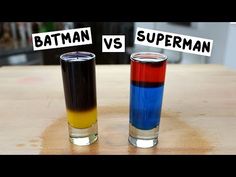 two shot glasses sitting on top of a wooden table next to each other with different colored liquids in them