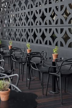 tables and chairs are lined up against the wall with planters on them in front of them