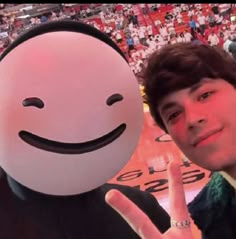 a young man holding up a peace sign next to a smiling face on a basketball court