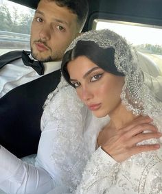 the bride and groom are sitting in the back seat of a car, dressed in white