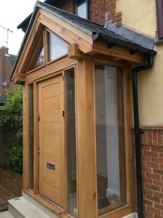 an outside view of a house with a wooden door and window on the side of it