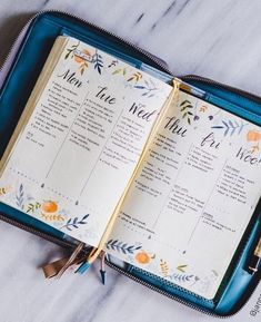 an open planner sitting on top of a blue case next to a pen and pencil