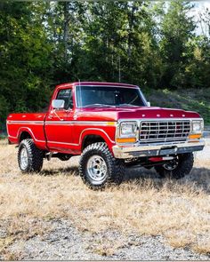 an old red truck parked in a field