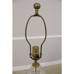 an antique brass and glass candle holder on a white floor with a wall in the background