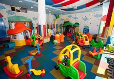 children's play area with toys and slides in large room, colorful carpeted flooring