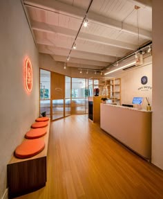 the inside of an office with wooden floors and orange stools in front of it